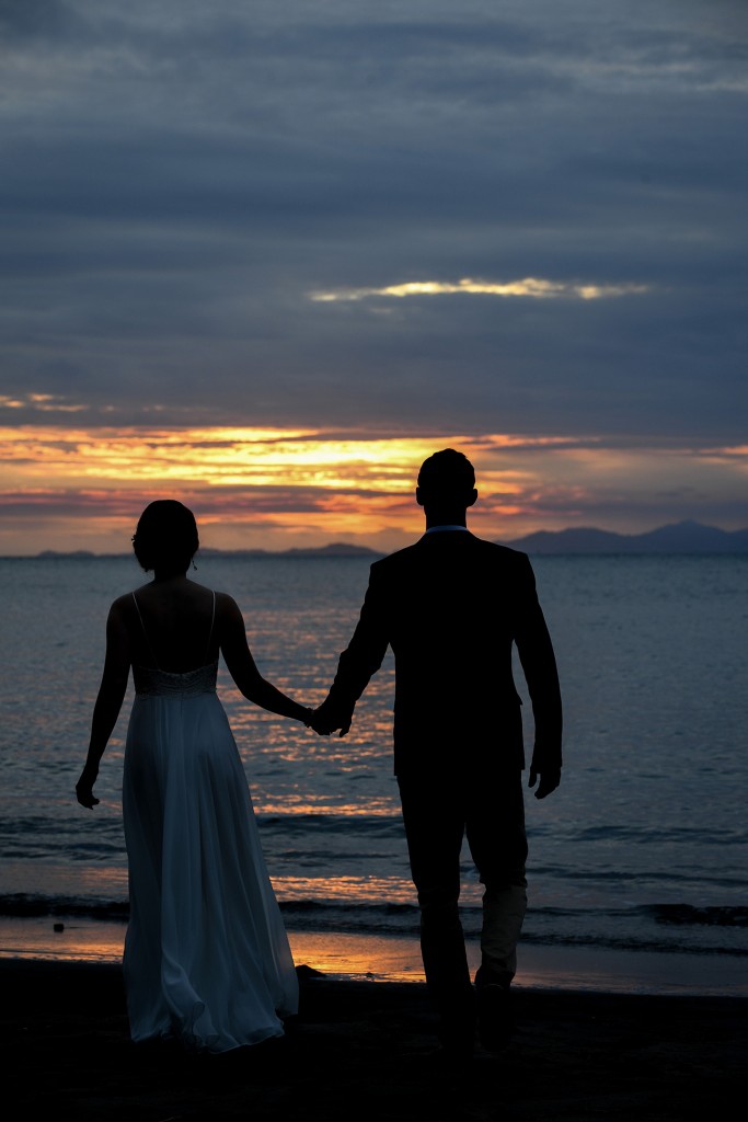 The bride and groom stroll towards the fiery sunset