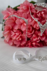 Earrings rest on a white ribbon as diamond necklace rests on a fuschia bouquet