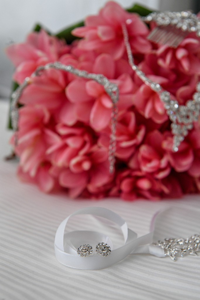 Earrings rest on a white ribbon as diamond necklace rests on a fuschia bouquet