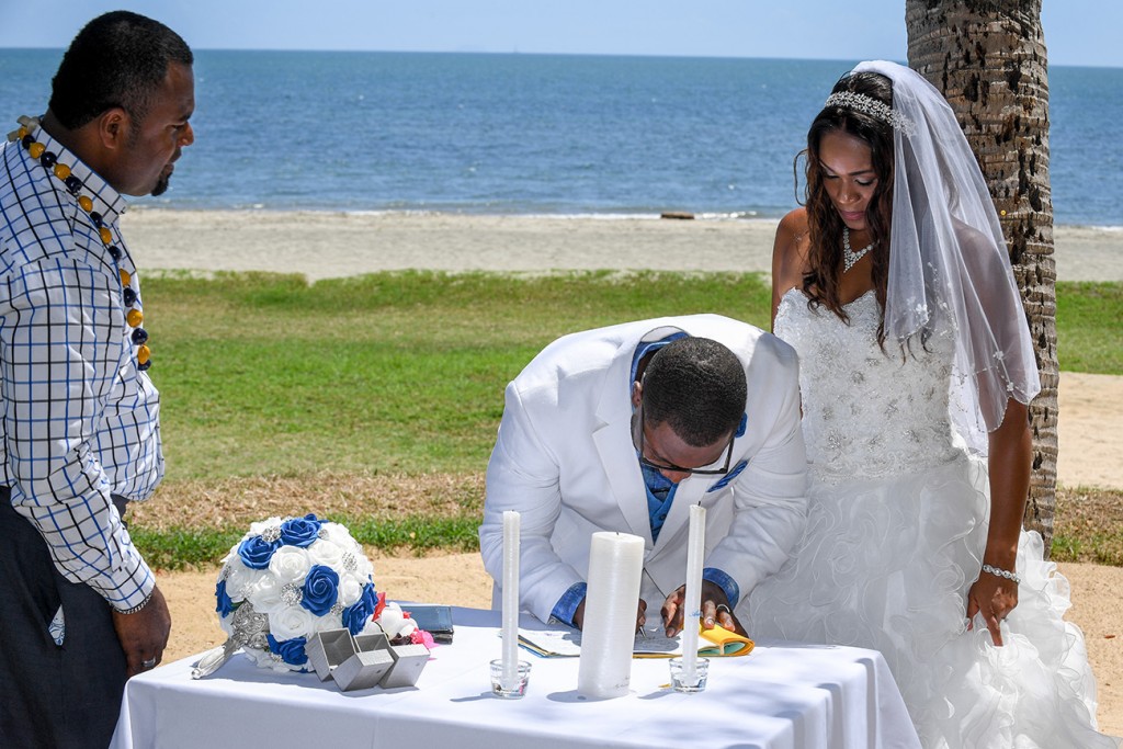 The bride and groom sign their wedding certificates overlooking the beach