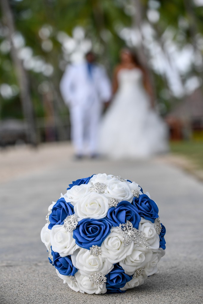 The bride and groom pose behind the Blue and white studded rose bouquet