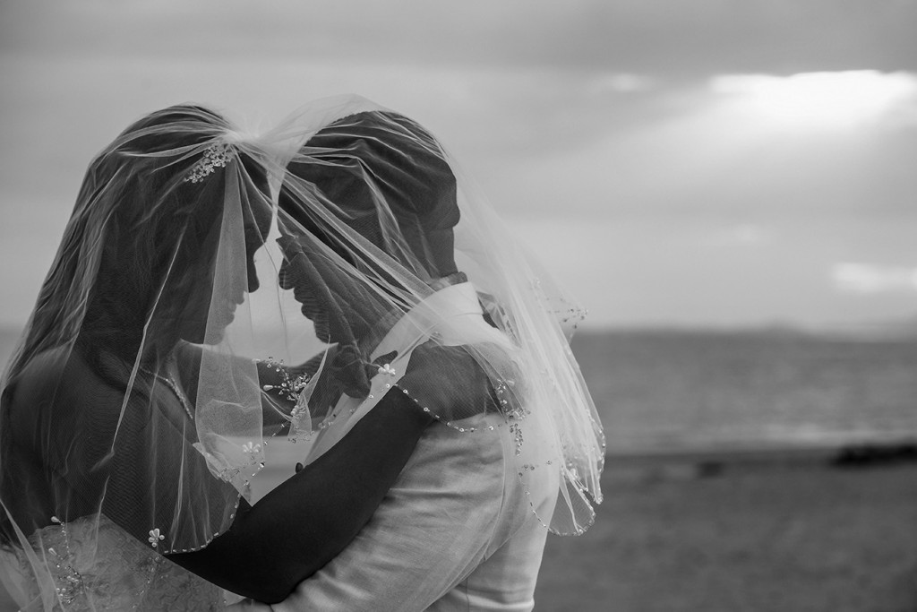 A monochrome photo of the bride and groom under the bride's veil