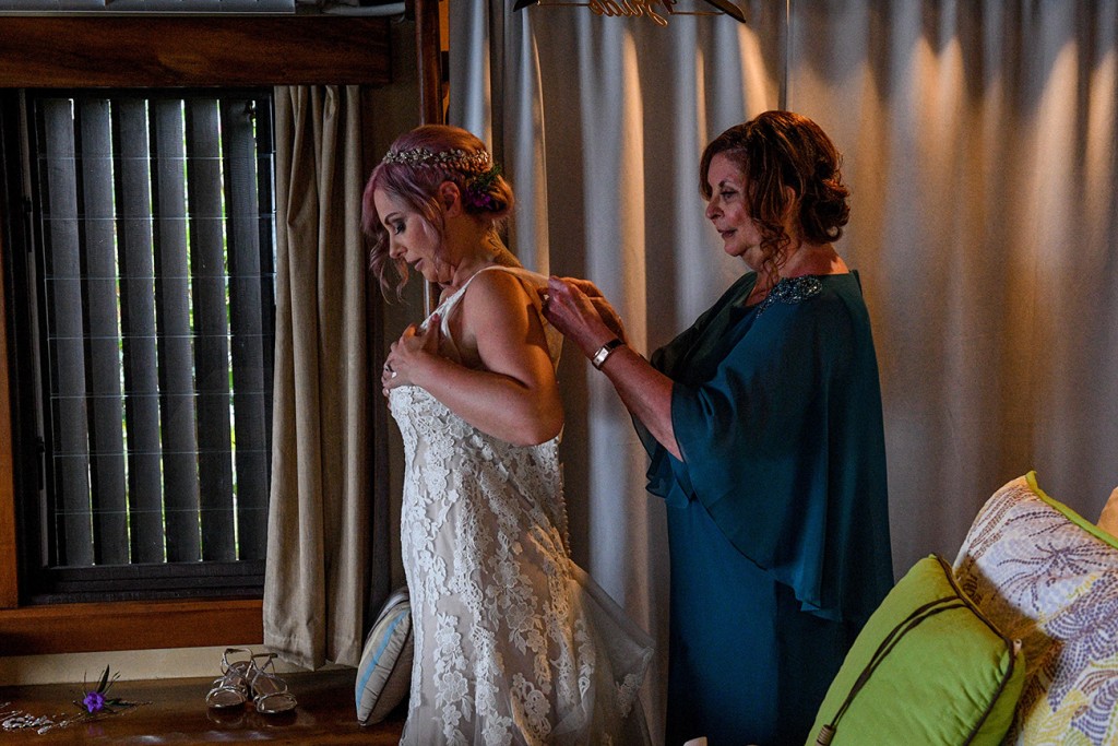 The bride's mother helps her daughter into her dress