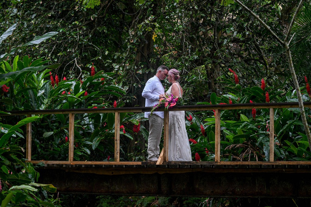 The newly weds share an intimate hug atop a bridge at the tropical rain forest