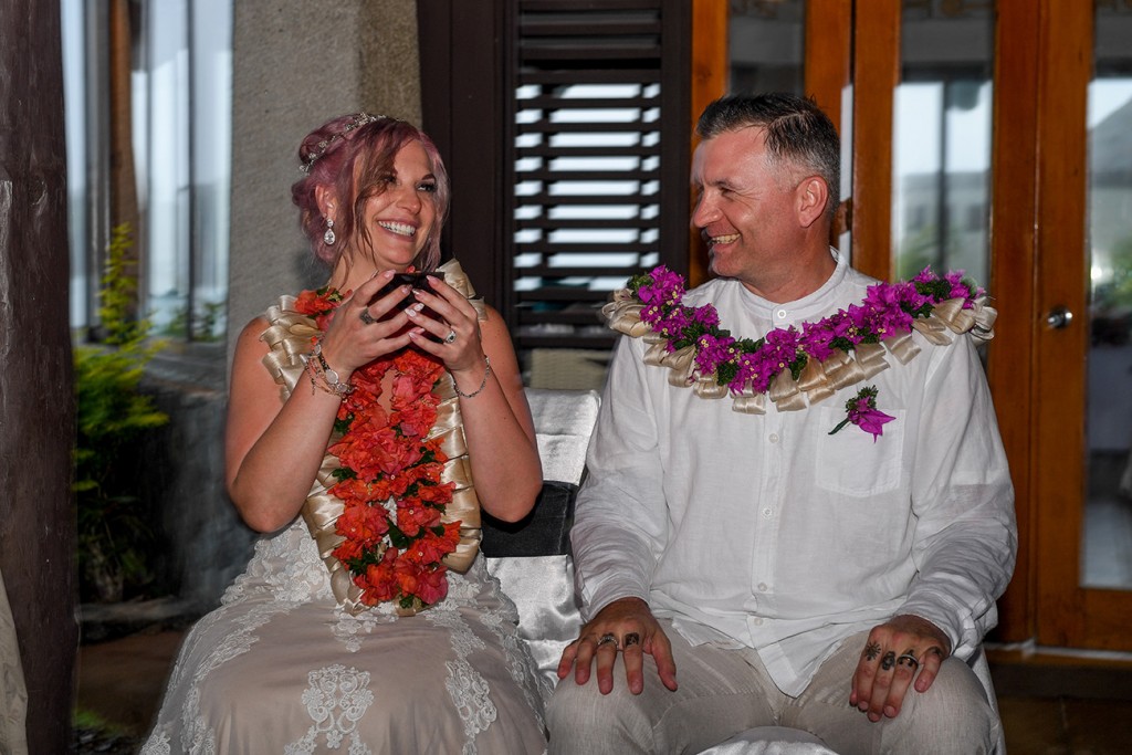 The bride smiles at her husband, both adorned in traditional Fiji wreaths