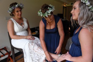 A bridesmaid slips a silver slipper onto the bride's foot