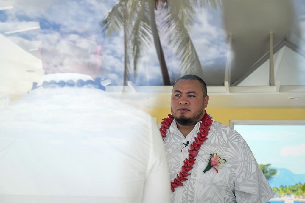 The groom waits nervously with a palm tree reflection in the foreground