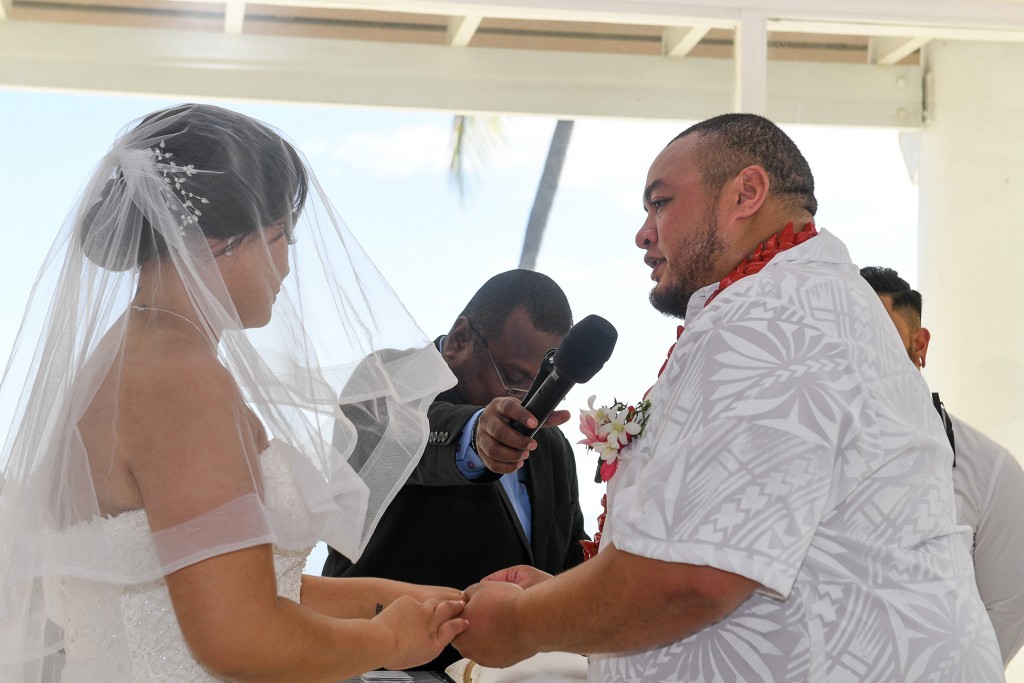 The groom says his vows as he puts the ring on his bride's finger