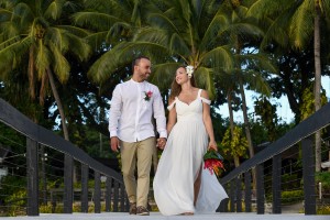 The couple strolls hand in hand on the Fiji dock against palm trees
