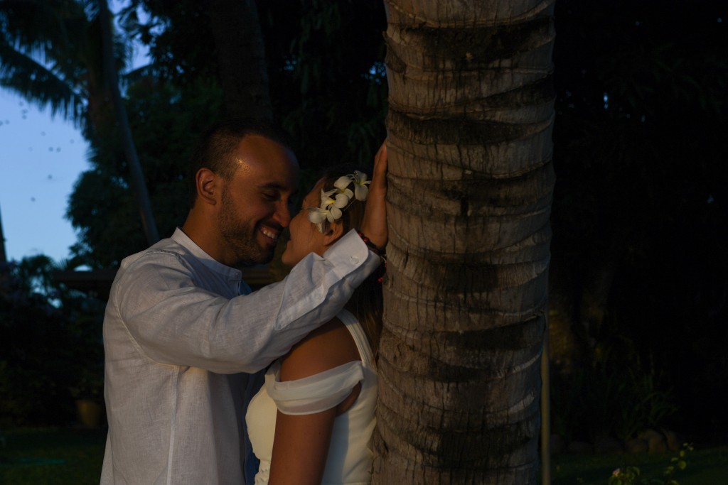 The couple share an intimate moment against a palm tree