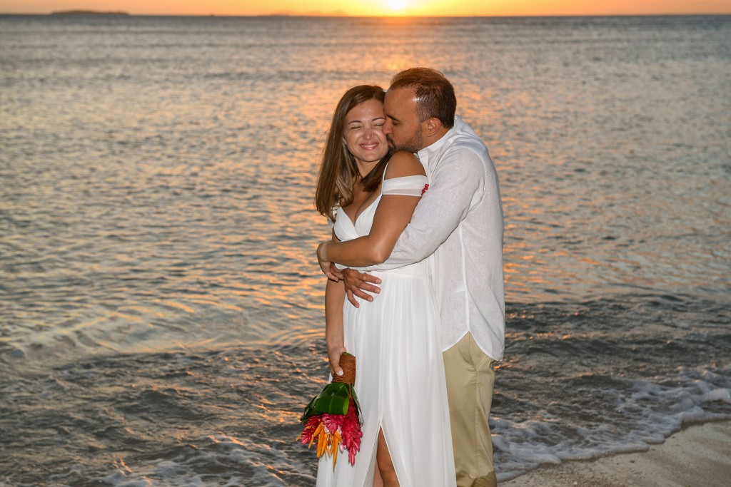The couple share an intimate kiss in the ocean against the golden Fiji sunset