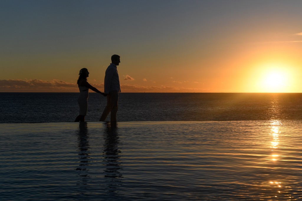 A silhouette of the couple strolling along the ocean at sunset