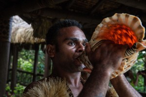A man blows on a traditional Fiji shell horn