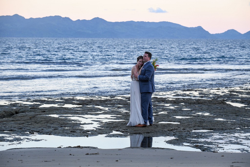 The couple embraces on the black sand beach