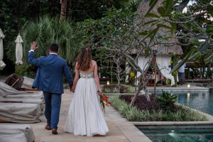 The newly weds wave as they stroll beside their personal pool