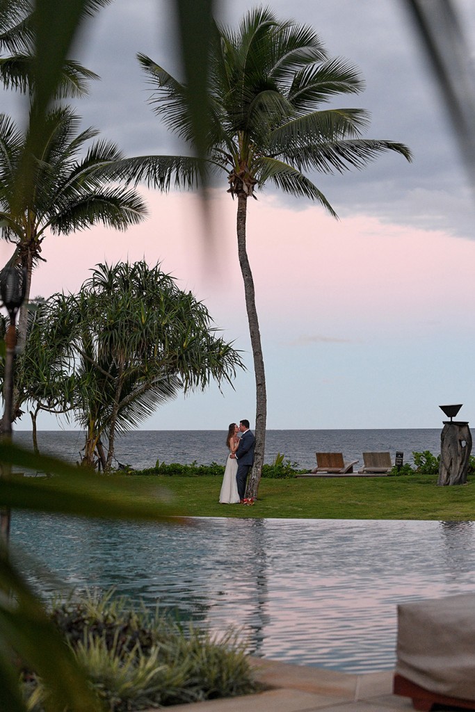 The newly weds kiss against towering palm trees at Nanuku Island Fiji