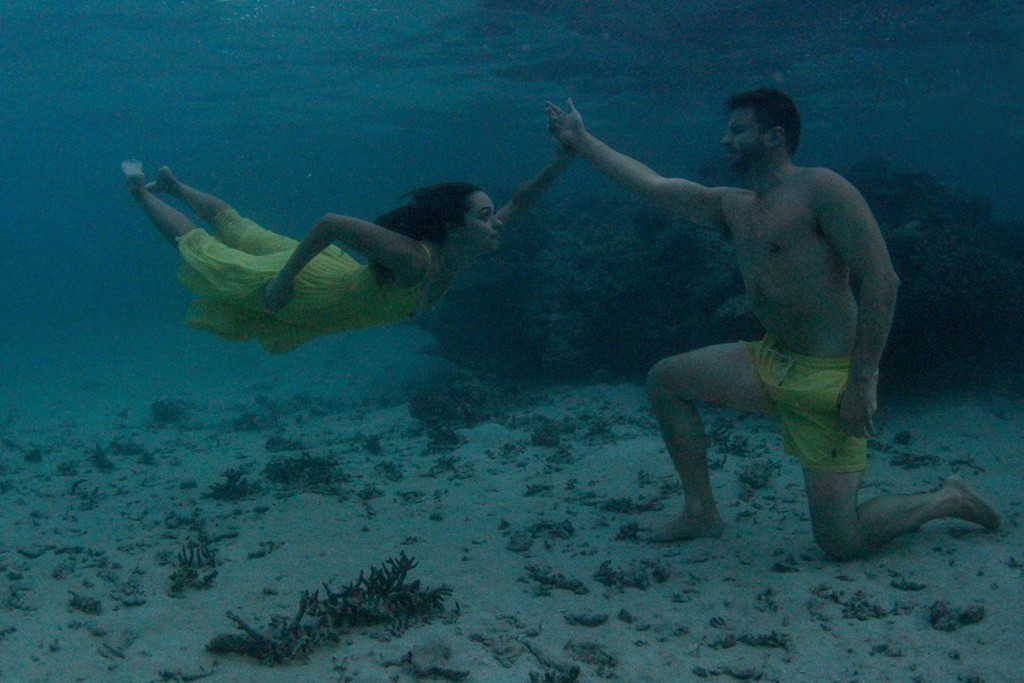 The couple high fives underwater