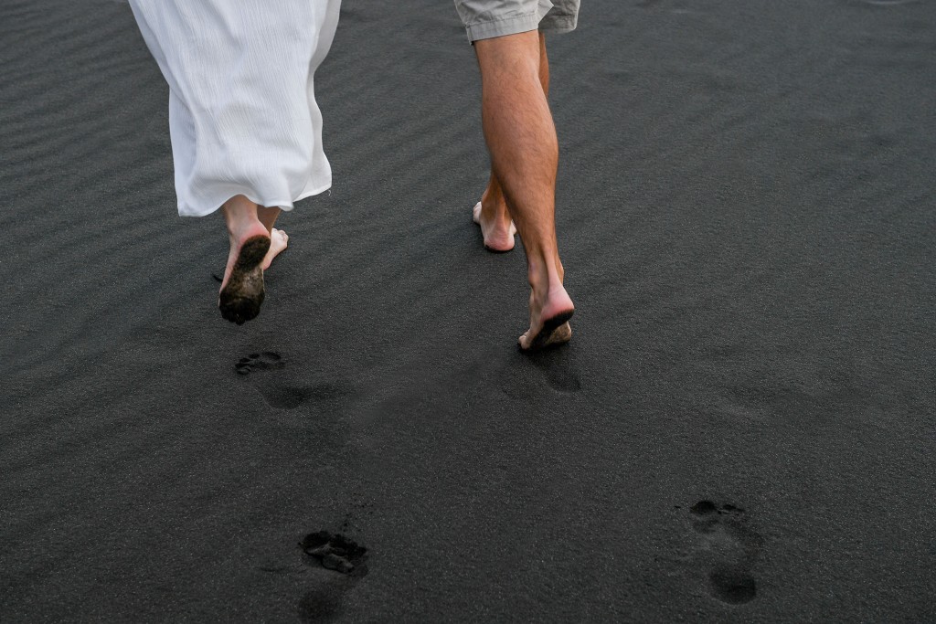 The newly weds leave footprints in the black sand at Karekare