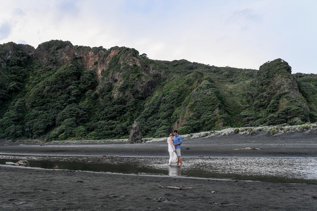 The newly weds stroll in the river at Karekare beach