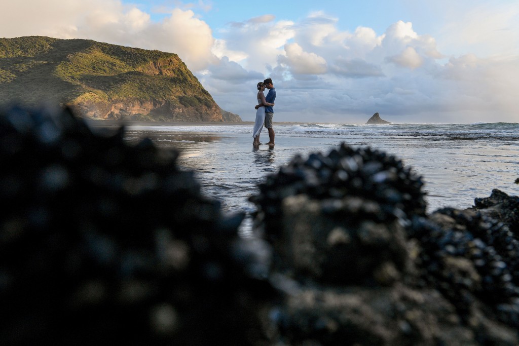A long shot of the newly weds standing in the black sand beach