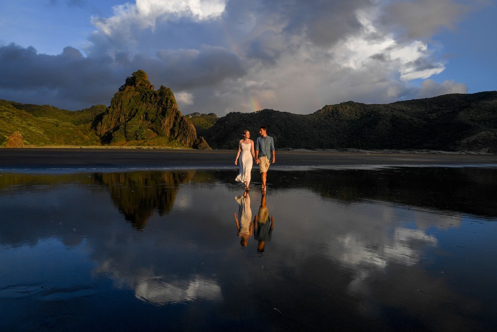 The newly weds stroll on black sand beaches at Karekare