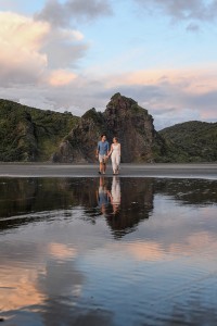 The married couple stroll at the edge of black sand beach