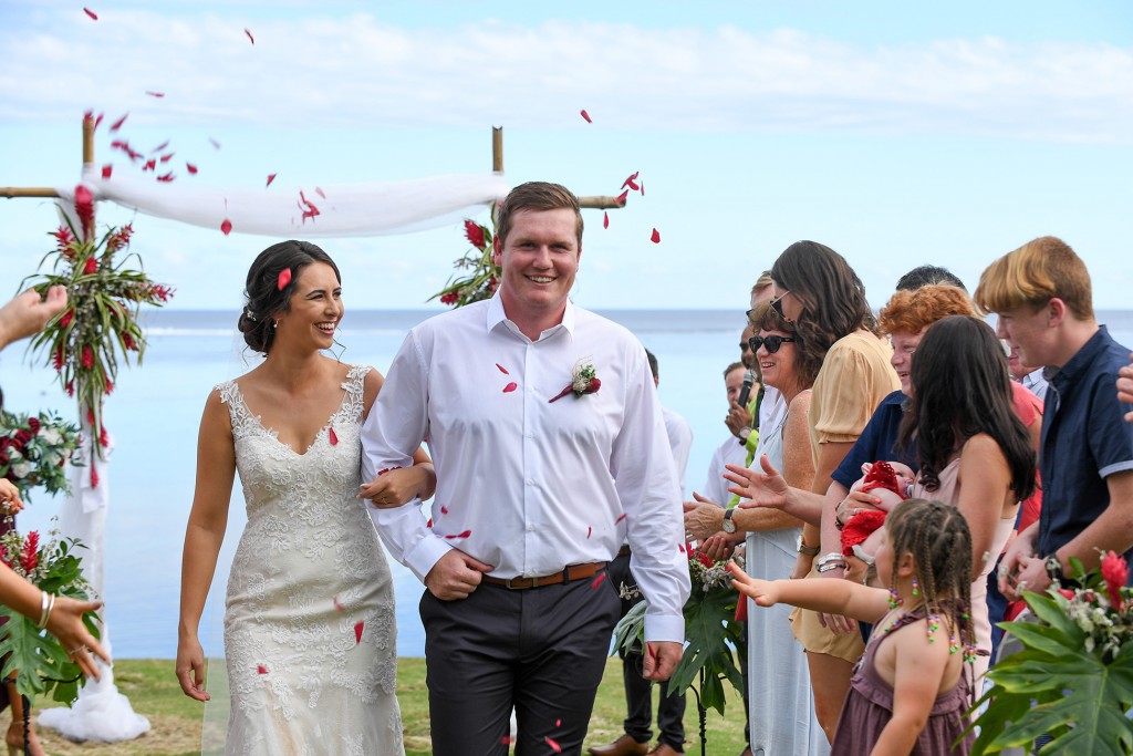 Red rose petals are thrown over the newly weds as they walk down the aisle