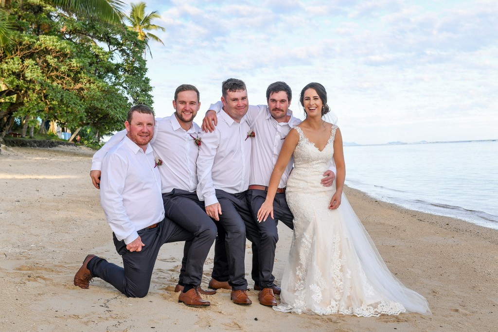 The bride poses with the groomsmen at the beach