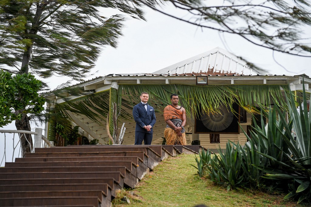 The groom and a traditional Fiji warrior await the bride