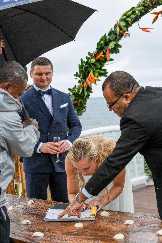 The celebrant shows the bride where to sign on the marriage certificate