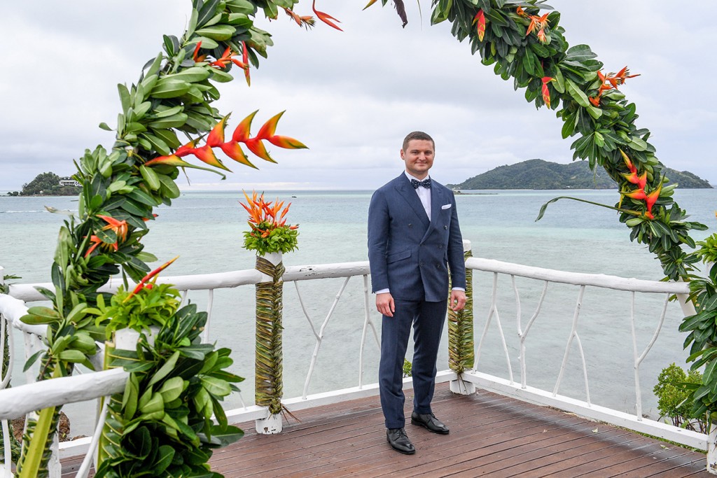The groom poses at the altar by the Pacific ocean
