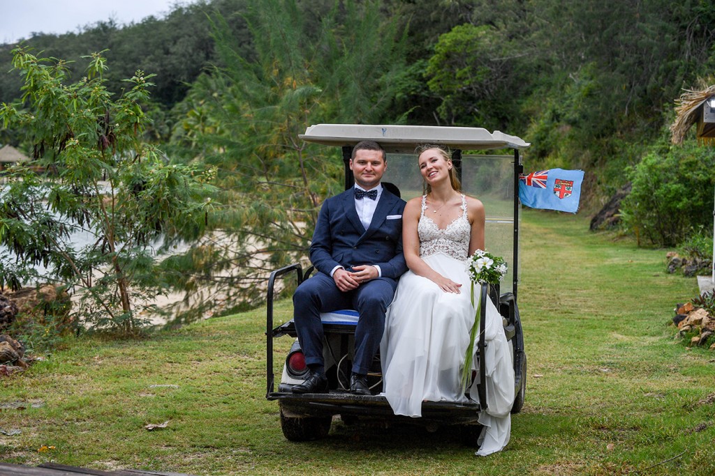The newly weds leave in a golf cart