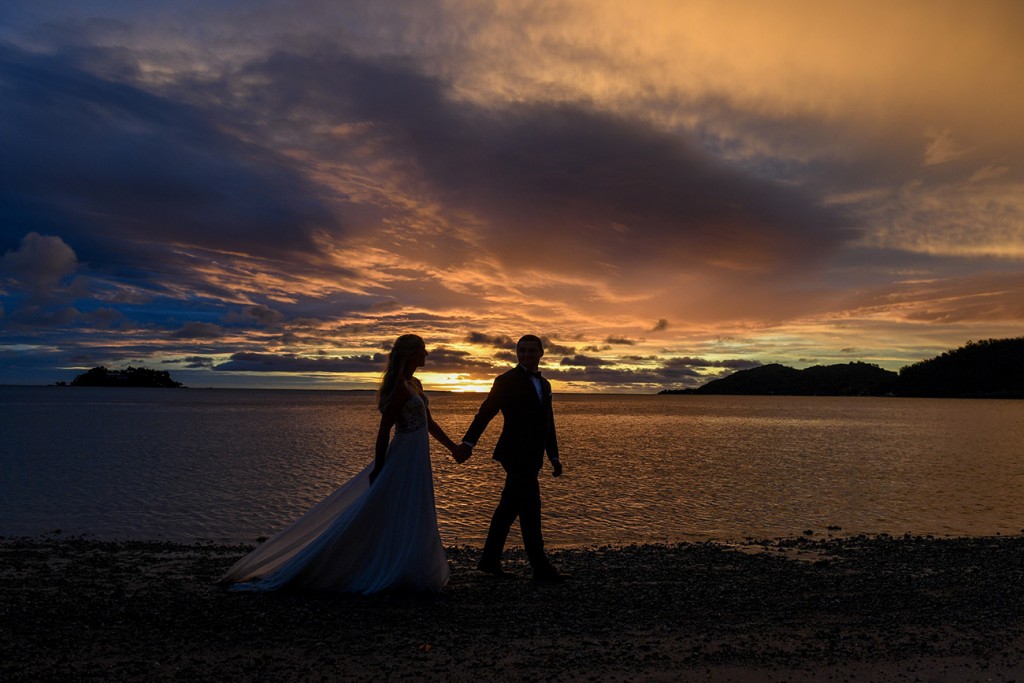 A silhouette of the newly weds strolling along the shores of the Pacific