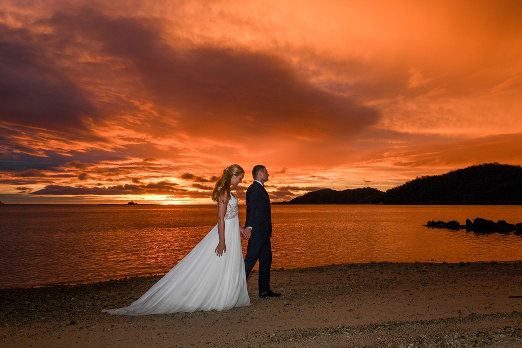 The newlyweds stroll on the shores of the Pacific during a fiery Fiji sunset
