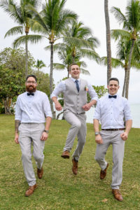 The groom jumps with his groomsmen under towering Fiji palm trees