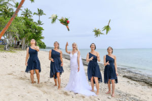 The bride and her bridesmaids toss their bouquets as they walk down the beach at Shangri La Fiji