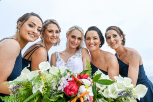 Smiling bride and bridesmaids pose with their bouquets