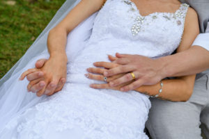An portrait of the bride and groom getting cosy with closeup on their wedding bands