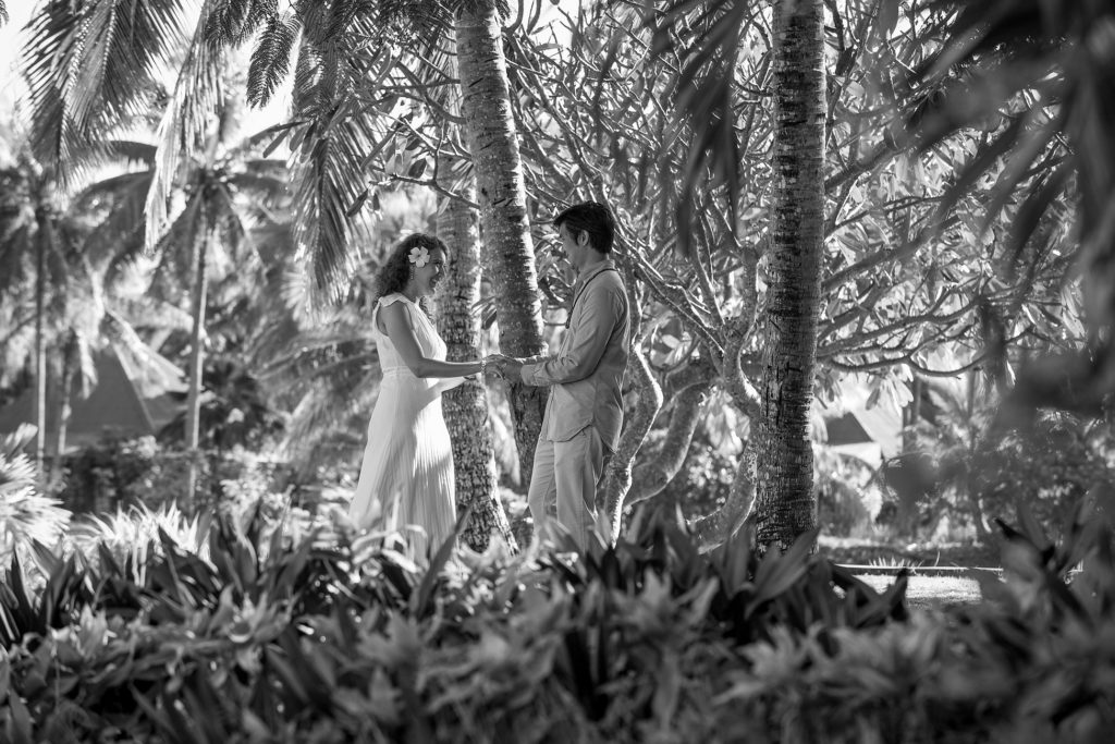 A monochrome frame of the loving couple holding hands under the palm trees of Malolo Island Fiji