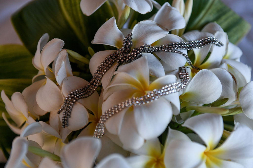The bride's v necklace draped on a bouquet of white frangipani flowers