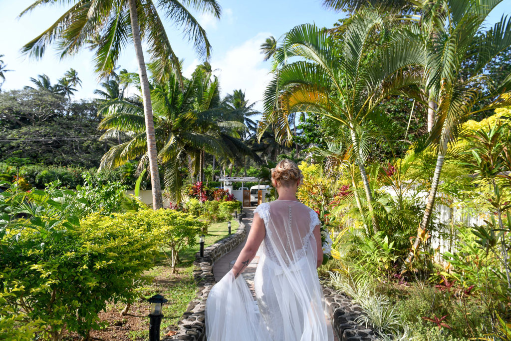 The bride walks down an aisle of towering Fiji palm trees