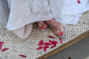 Rose petals at the foot of the bride's clear strapped heel