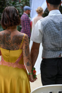 A tattooed wedding guest watches the ceremony