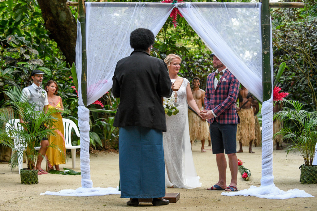 The bride and groom hold hands while at the altar