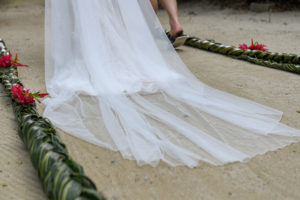 The bride's wedding train being dragged along the sand
