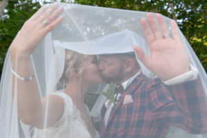 The loving couple passionately kiss under the bride's veil