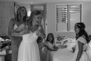 A monochrome image of the the happy bride fitting her wedding dress