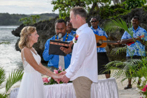 The newly weds hold hands as they say their vows overlooking the beach