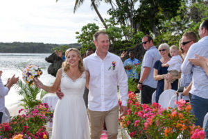 The newly weds happily walk down the aisle cheered by guests