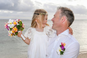 The flower girl sits on the groom's lap at Shangri La beach